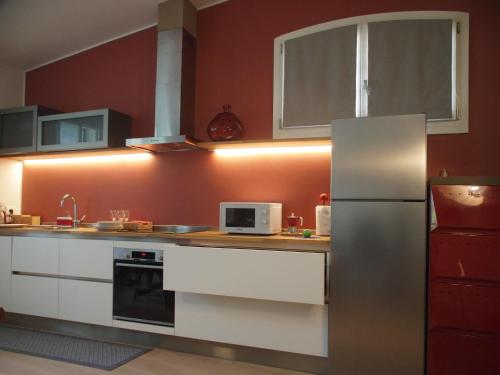 a kitchen with white cabinets and a stainless steel refrigerator at Foresteria Conti, sulle tracce di Shakespeare in Padova