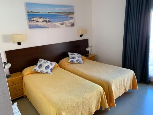 two beds in a room with a view of the ocean at Hotel Maria Teresa in Sant Antoni de Calonge