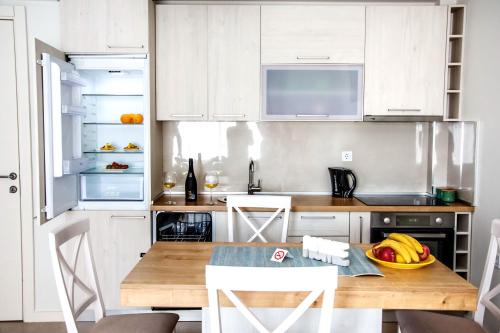 a kitchen with white cabinets and a wooden table at Ralux apartman Tivat in Tivat