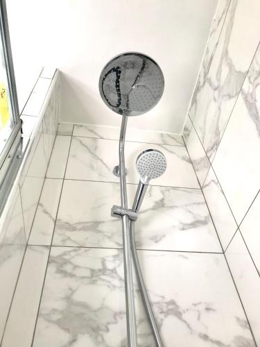 a shower in a bathroom with white tiles at Residence Hoche in Le Pré-Saint-Gervais