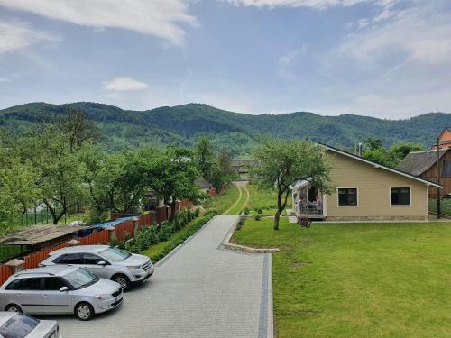 two cars parked in a driveway next to a house at Lucy in Yaremche