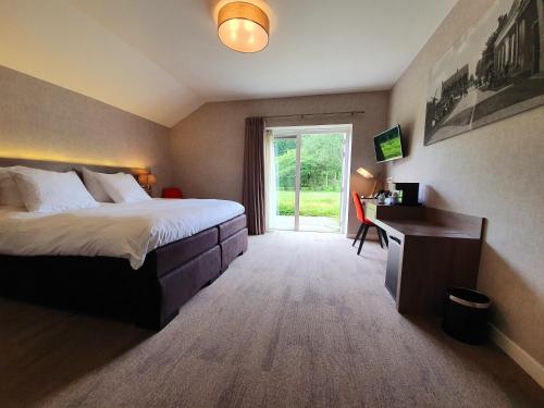 a bedroom with a bed and a desk and a window at Schaluinenhoeve in Baarle-Nassau