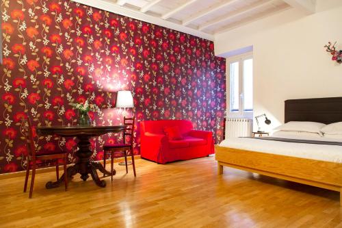 a bedroom with a bed and a red chair at Paglia House of 17Century in Trastevere in Rome