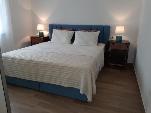 a bed with a blue headboard and two night stands at Holiday House Elena in Fažana