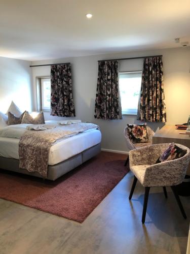 a bedroom with a bed and a chair and windows at Hotel Restaurant Der Engel, Sasbachwalden in Sasbachwalden