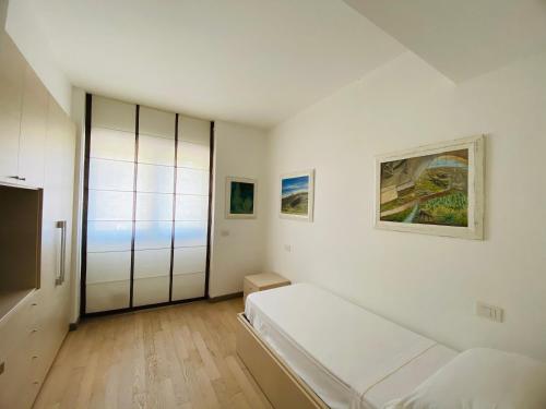 a white bedroom with a bed and a sliding glass door at La Villa nel Parco in Sanremo
