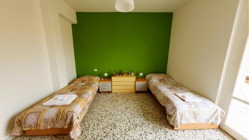 2 camas en una habitación con una pared verde en The Homestay - Arezzo, en Arezzo