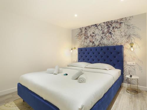 a large bed with a blue headboard in a room at Rent a Room - Apartment St Honore in Paris