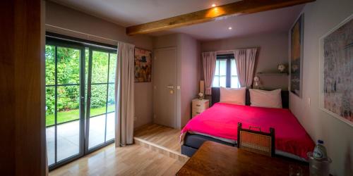 a bedroom with a red bed and a large window at B&B Yaca in De Haan