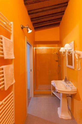 an orange bathroom with a sink and a shower at Bio Agriturismo Le Cascatelle in Saturnia