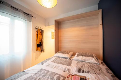 レ・サ​​ーブル・ドロンヌにあるMa Location Sablaise - Appart' Aragoのベッドルーム1室(木製ヘッドボード付きのベッド1台付)