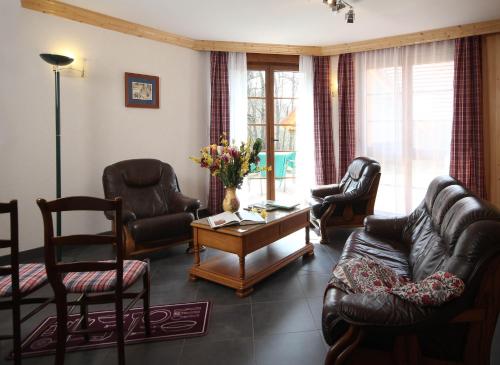 sala de estar con muebles de cuero, mesa y sillas en Les Gites La Cerisaie, en Breitenbach