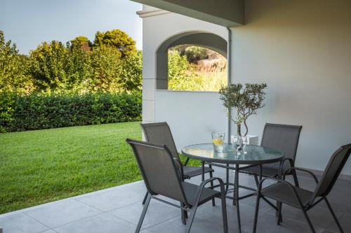 a glass table and chairs on a patio at ASTRA Village Resort in Svoronata