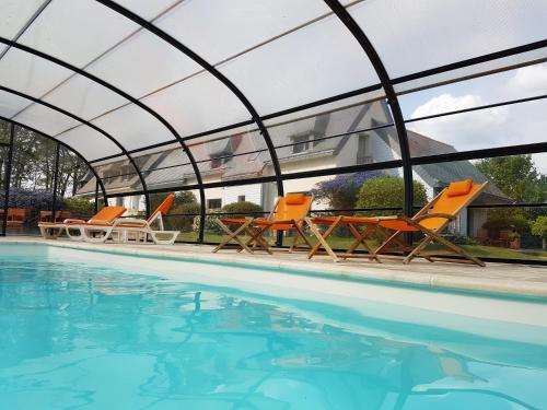 a group of orange chairs and a swimming pool at l'Arbre Voyageur in Locoal-Mendon