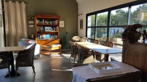 une chambre avec des tables, des chaises et une étagère à livres dans l'établissement l'Arbre Voyageur, à Locoal-Mendon