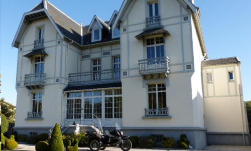 a motorcycle parked in front of a large house at La Roseraie in Saint-Étienne-au-Mont