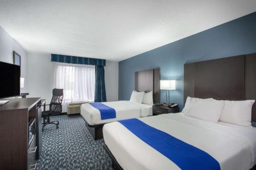a hotel room with two beds and a flat screen tv at University Inn & Suites in Charlotte