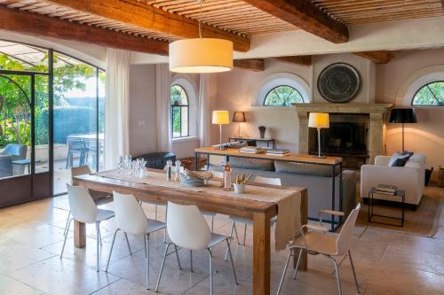 a dining room with a large wooden table and white chairs at Mas De Rosemarie in Joucas