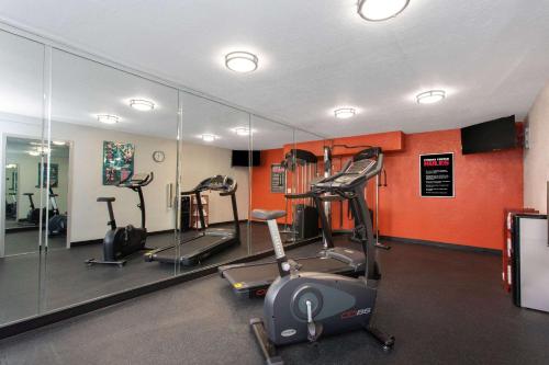 a gym with several tread machines and a mirror at Days Inn by Wyndham Orlando Conv. Center/International Dr in Orlando
