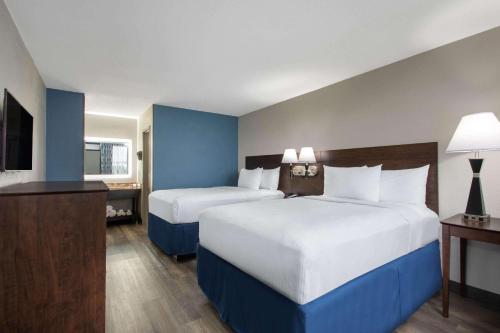 a hotel room with two beds and a television at Days Inn by Wyndham Orlando Conv. Center/International Dr in Orlando