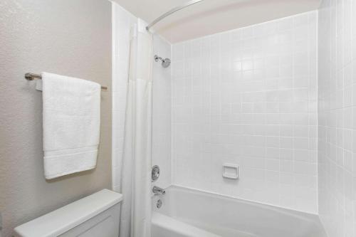 baño blanco con ducha y aseo blanco en Days Inn by Wyndham Orlando Conv. Center/International Dr en Orlando