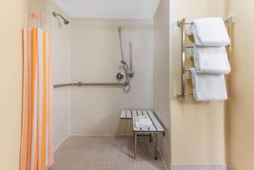 a bathroom with a shower with a bench and towels at La Quinta by Wyndham Fort Lauderdale Pompano Beach in Fort Lauderdale