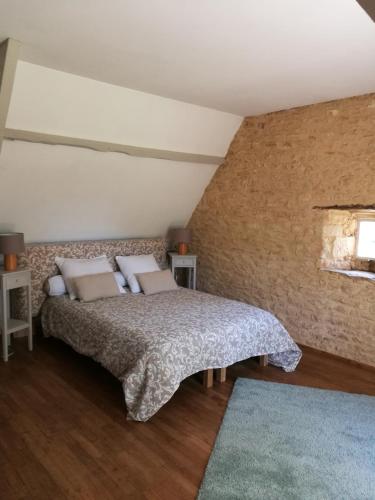 a bedroom with a bed and a brick wall at La Petite Vignolle in Saint-Amand-de-Coly