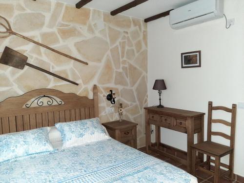 1 dormitorio con cama y pared de piedra en Casa Rural "Los Aperos", en Herrera del Duque