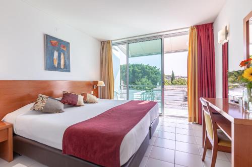 um quarto com uma cama, uma secretária e uma varanda em Hotel Sao Sebastiao de Boliqueime em Boliqueime