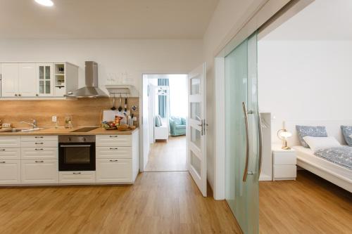 a kitchen with white cabinets and a living room at Apartments Villa Whitehouse in Ostrava