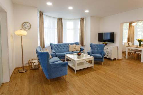 a living room with blue chairs and a tv at Apartments Villa Whitehouse in Ostrava