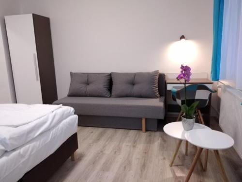 a small room with a couch and a table with flowers at Diana Panzió in Mátrafüred