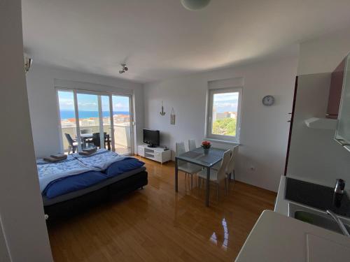 a bedroom with a bed and a table and a kitchen at Apartment Emmy in Novalja