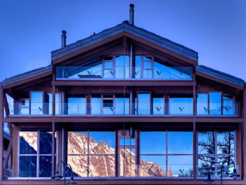 a building with glass windows and a mountain at Backstage Boutique SPA Hotel in Zermatt