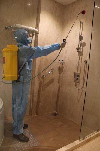 a man in a blue jumpsuit is painting a shower at Ramada by Wyndham Gandhidham Shinay in Gandhidham