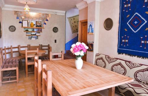 uma sala de jantar com uma mesa e um vaso com flores em A Secret Garden em Tinghir