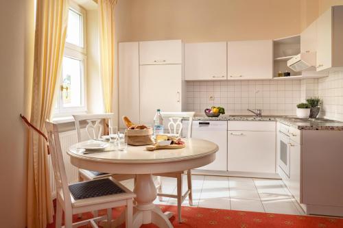 eine weiße Küche mit einem Tisch und Stühlen im Zimmer in der Unterkunft Klosterhof St. Salvator in Bad Griesbach