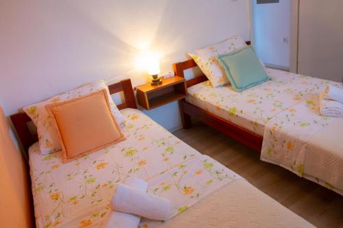 a bedroom with two beds and a table with a lamp at APARTMENT TONY - 2bdr Beachfront in Jadrija