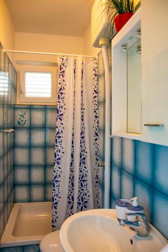a bathroom with a sink and a shower curtain at APARTMENT TONY - 2bdr Beachfront in Jadrija