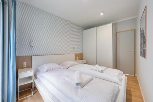a bedroom with a white bed with white towels on it at Apartamenty Sun & Snow Aura III in Gdańsk