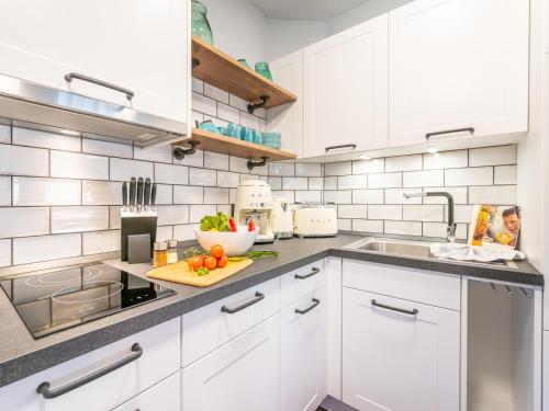 a kitchen with white cabinets and a sink at OSTSEELOFT BINZ - Villa Amanda WG 08 in Binz
