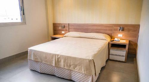 a bedroom with a large bed and two night stands at Hotel Santa Maria by RB Hotelaria in Campo Mourão
