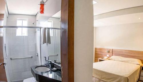 a bathroom with a bed and a sink and a shower at Hotel Santa Maria in Campo Mourão