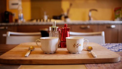 dos tazas de café y cucharas en una tabla de cortar de madera en The Homestay - Arezzo en Arezzo