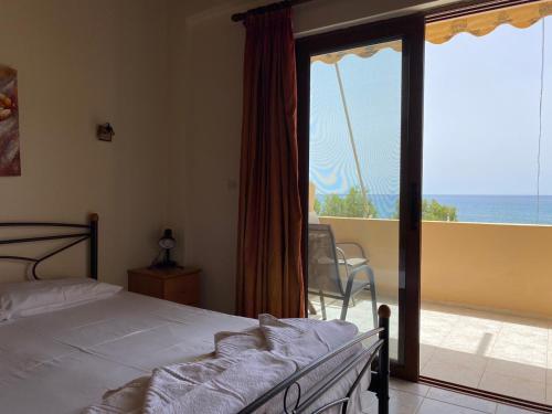 a bedroom with a bed and a view of the ocean at Apanemia Rooms in Triopetra