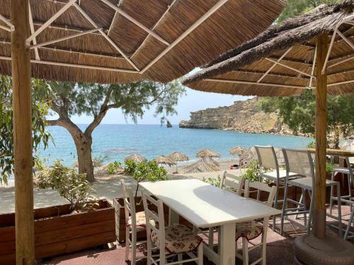 a table and chairs on a beach with the ocean at Apanemia Rooms in Triopetra
