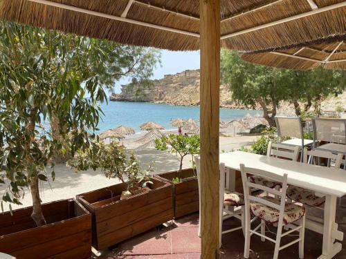 a table and chairs under an umbrella on the beach at Apanemia Rooms in Triopetra