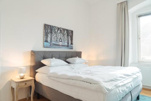 a bedroom with a large bed with white sheets and pillows at Smile Apartments zur Gozzoburg in Krems an der Donau