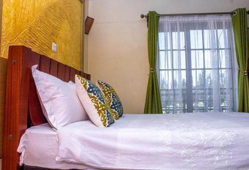 Un dormitorio con una cama blanca con una ventana. en Kasty L Studios and Apartments, en Nairobi
