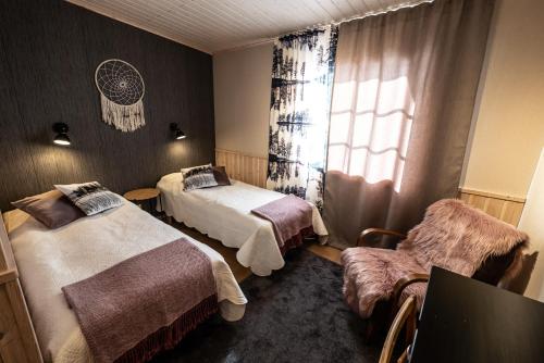 una camera d'albergo con due letti e una finestra di Isokenkäisten Klubi - Wilderness Lodge a Kiviperä